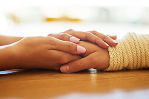 One hand holding another person's hand, providing support and comfort. One hand holding another person's hand, providing support and comfort.