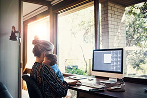 A mother at home browsing the internet on her home computer.